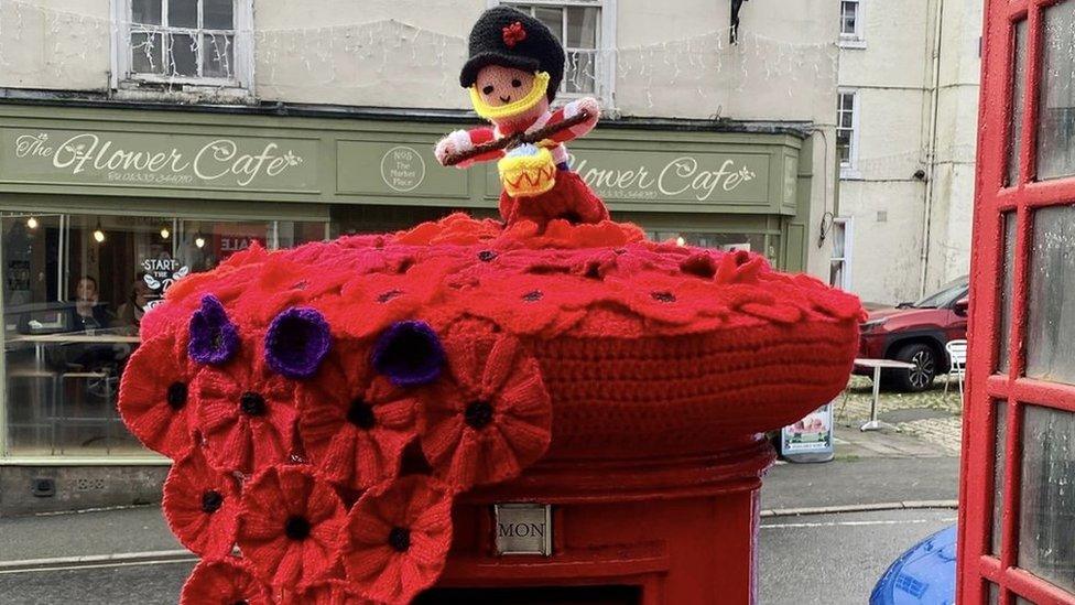 Knitted poppies and figure on a postbox topper in Ashbourne