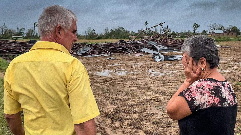 Owners of a tobacco house look at the destruction in Cuba