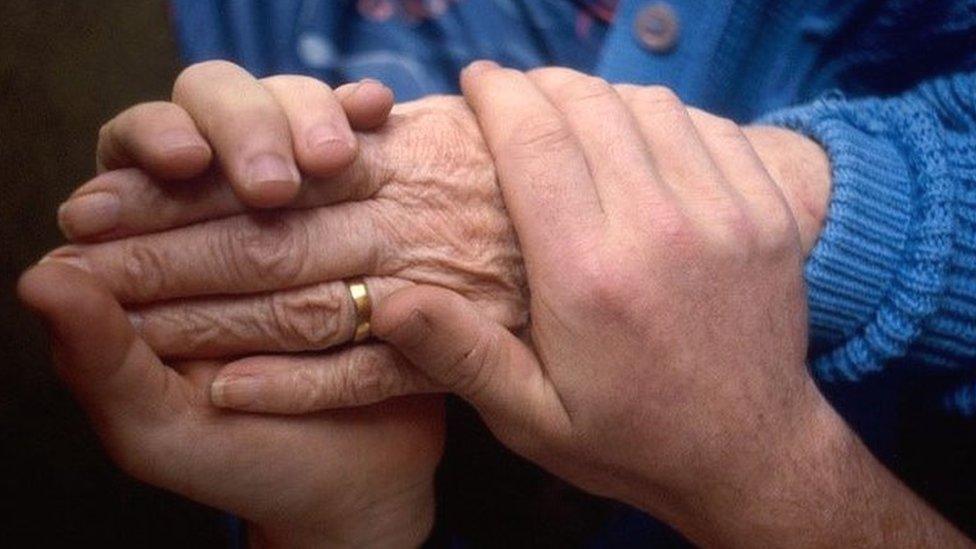 A younger person holding an older person's hands