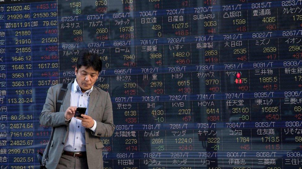 Man stands in front of stock boards in Japan