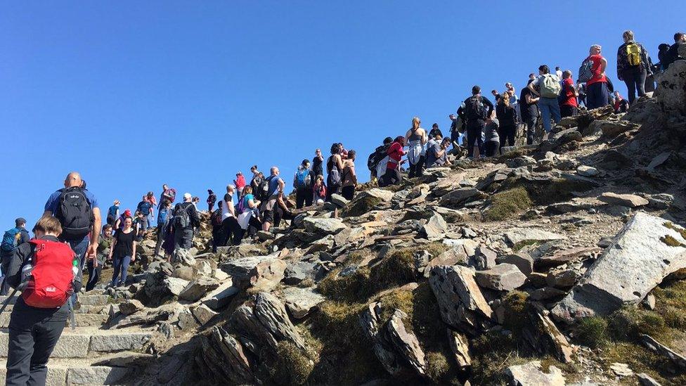 Crowds of people near trig point