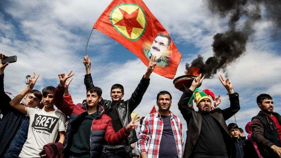 Kurdish men hold up a flag with a picture of the jailed PKK leader Abdullah Ocalan during Newroz celebrations in Diyarbakir