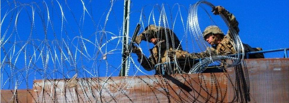 US military soldiers install barbed wire on the border with Mexico as seen from Colonia Libertad in Tijuana, Mexico