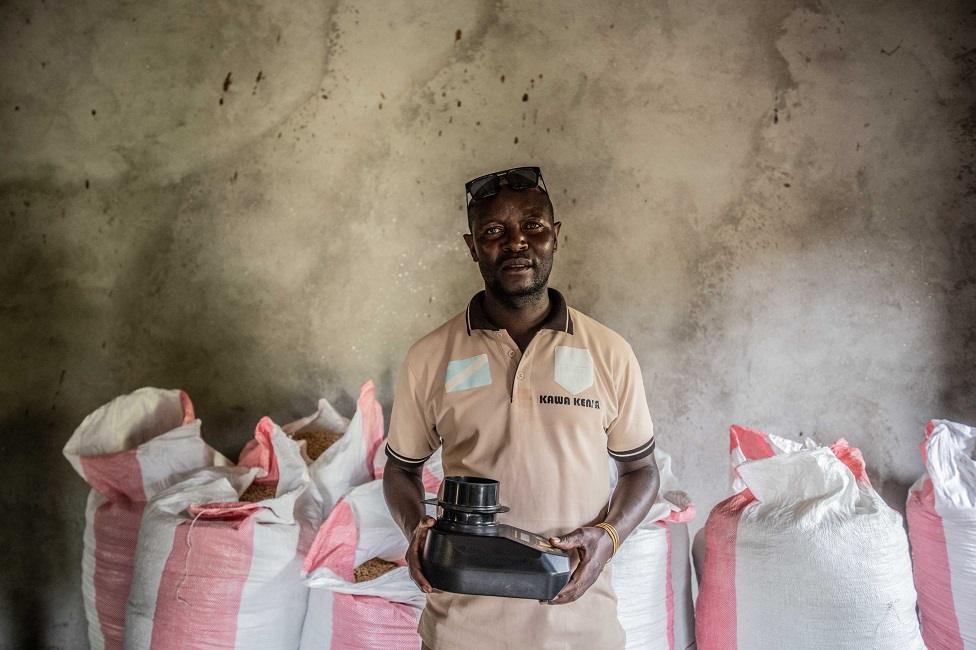 Koko Bikuba, 37-year-old former combatant, holds a refractometer to measure the temperature of the coffee.