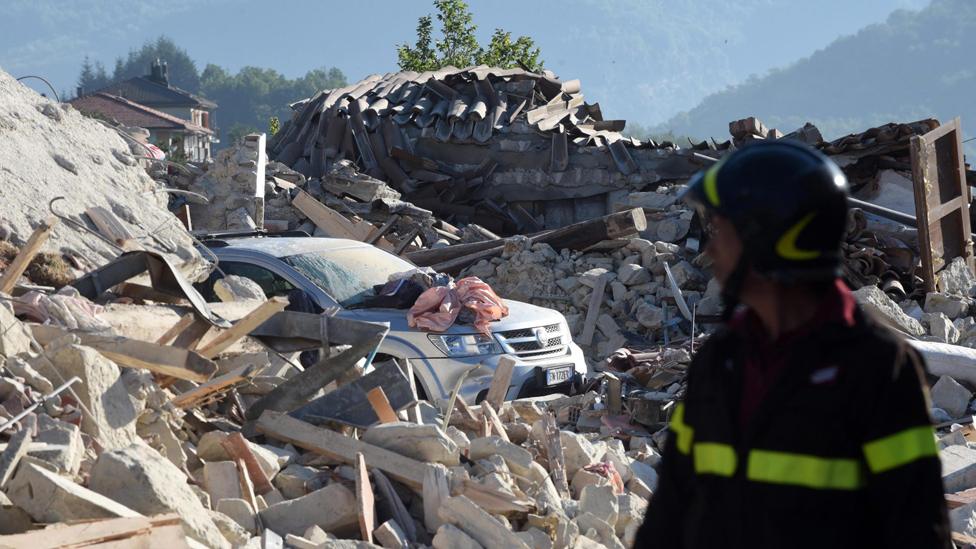 A firefighter observes the rubble of a collapsed building in Pescara del Tronto, 25 Aug 16