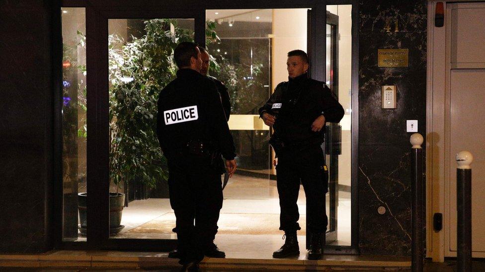 French police officers stand guard at the entrance of the building where British photographer David Hamilton was found dead at his home