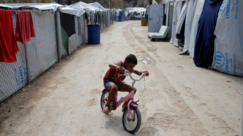 A boy rides a bicycle at the Souda municipality-run camp for refugees and migrants, on the island of Chios, Greece, 7 September 2016