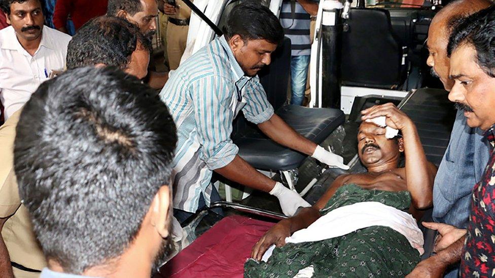 Indian medical officials and bystanders carry an injured man from a vehicle into a hospital in Paravur