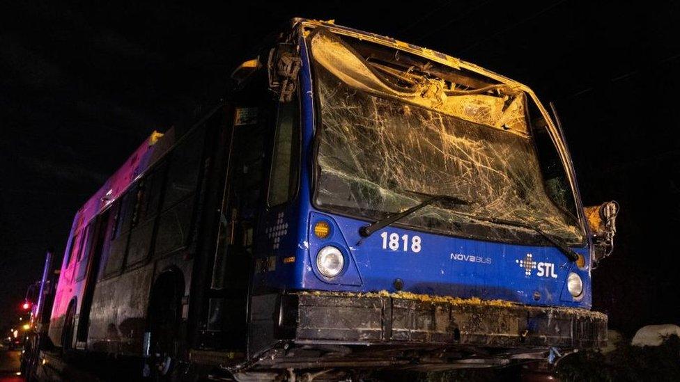 Photo of shattered front windows of city bus, as the vehicle is getting towed away