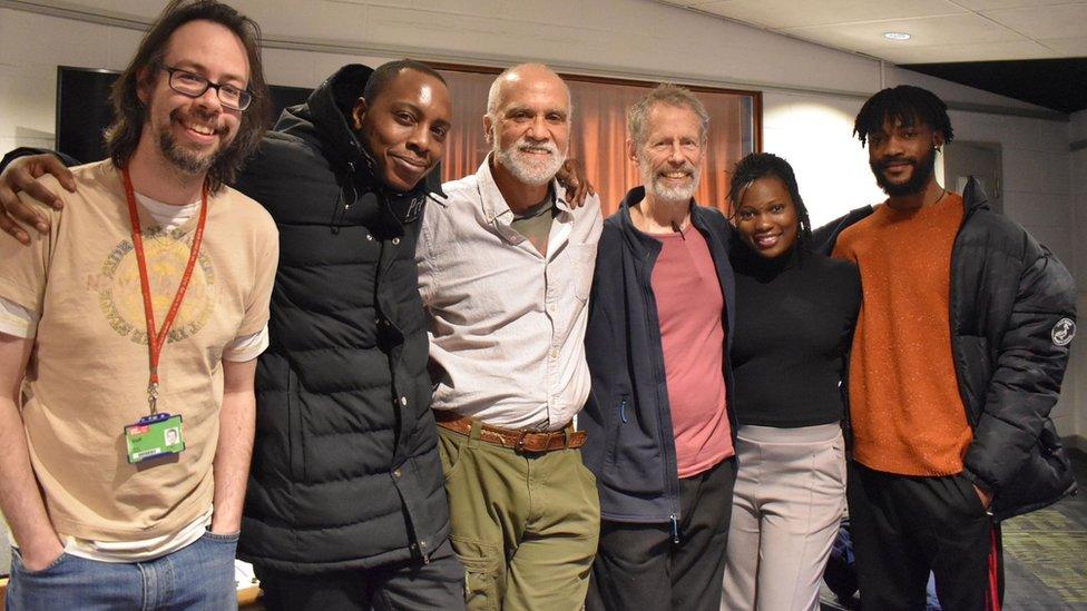 Ralph Hoyte stands in the centre of a line of five other people, with hands on each others shoulders, who worked on the project with him all smiling and looking at the camera