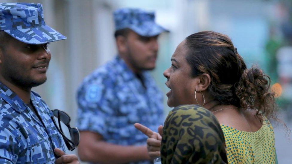 A Maldivian opposition activist argues with a policeman outside parliament in Male on March 27, 2017.