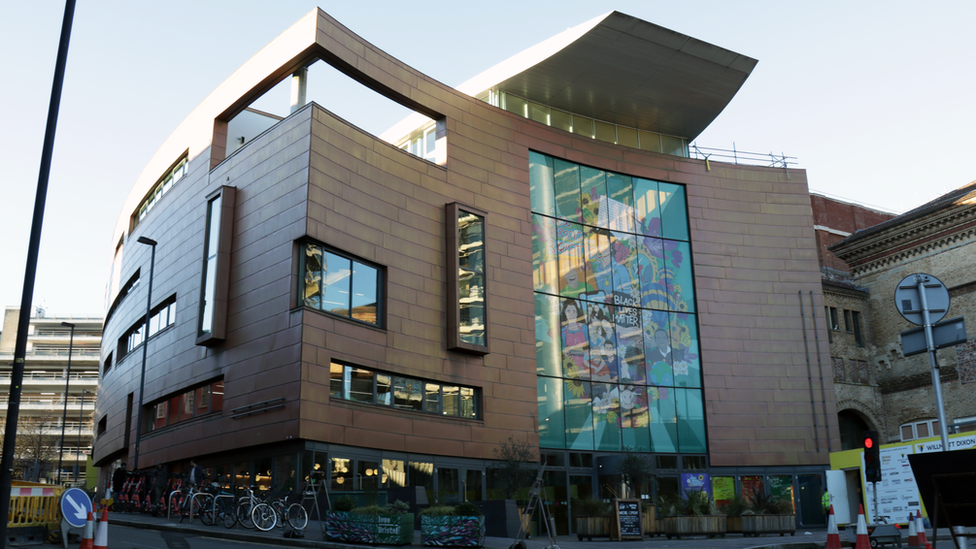 A picture of the Bristol Beacon building from the front. It is low light and there is Black Lives Matter artwork on the front windows.