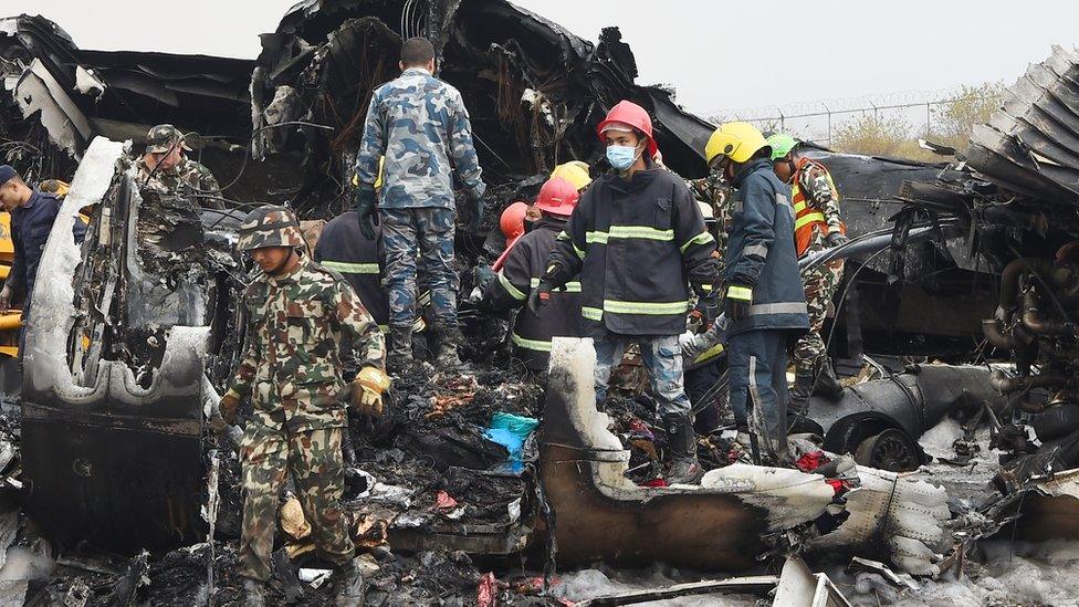 Nepali rescue workers remove a body found in the wreckage of an airplane that crashed near the international airport in Kathmandu on March 12, 2018. Forty-nine people were killed when a Bangladeshi plane crashed and burst into flames near Kathmandu airport on March 12, in the worst aviation disaster to hit Nepal in nearly three decades.