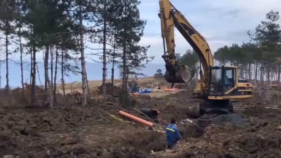 A digger at work next to a beach