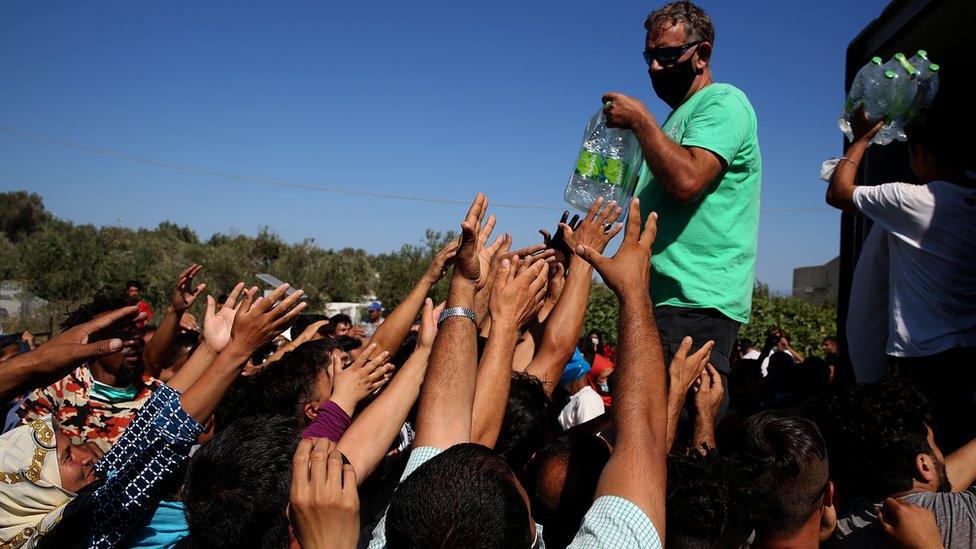 Migrants receive food, fruit and water near the sit of the Moria camp on the island of Lesbos, Greece, 10 September 2020