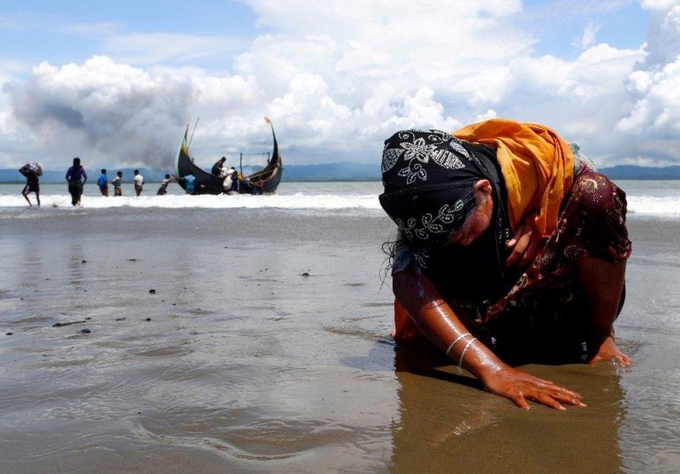 An exhausted Rohingya refugee woman touches the shore after crossing the Bangladesh-Myanmar border by boat through the Bay of Bengal, in Shah Porir Dwip, Bangladesh September 11, 2017.