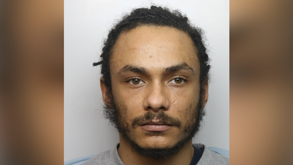 A mugshot of Michael Christian - dark hair and a wispy beard, and a grey sweatshirt 