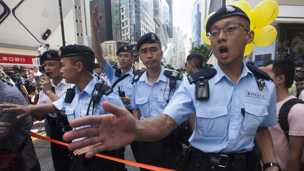 Hong Kong police officers clear a street near the Sogo department store in Causeway Bay before the annual pro-democracy march begins, Causeway Bay, Hong Kong, China, 01 July 2018.