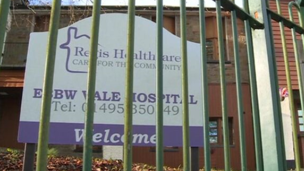 A picture of Regis Healthcare's sign behind a barred fence