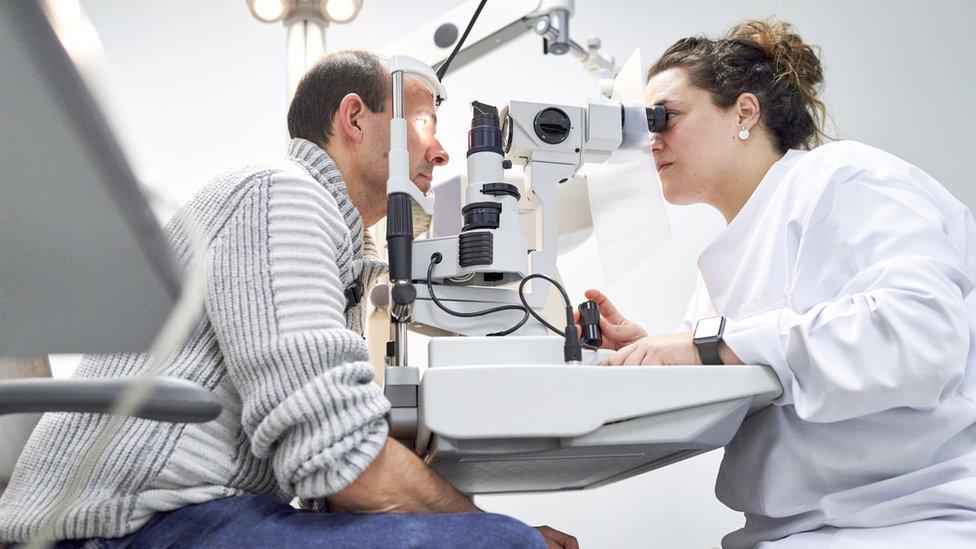 Female ophthalmologist examining male patient in ophthalmology clinic with autorefractometer, examination of eyesight. - stock photo