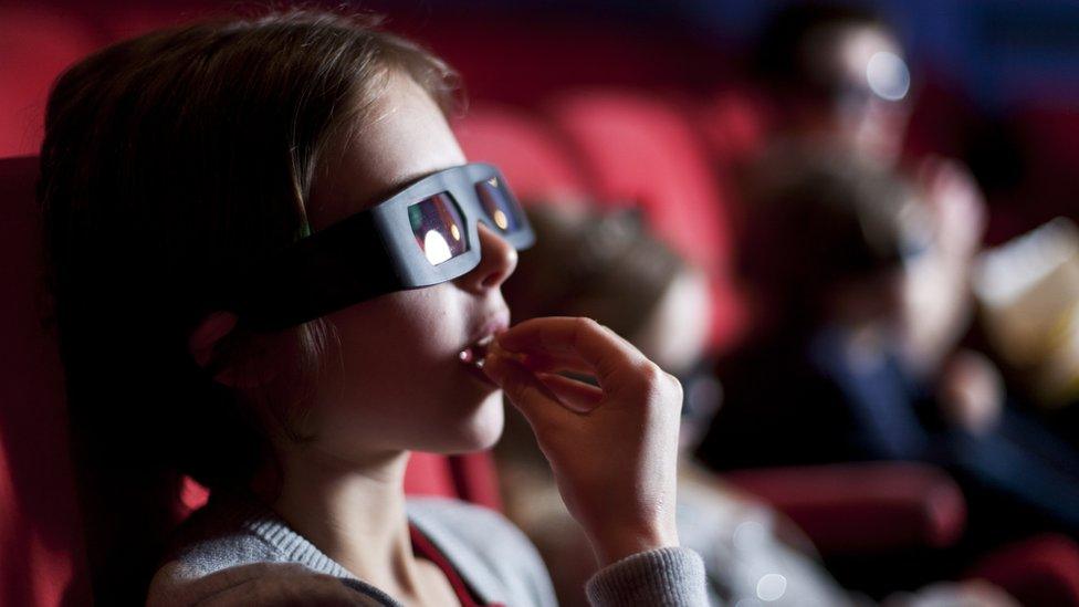 A girl eats popcorn whilst watching a 3d movie