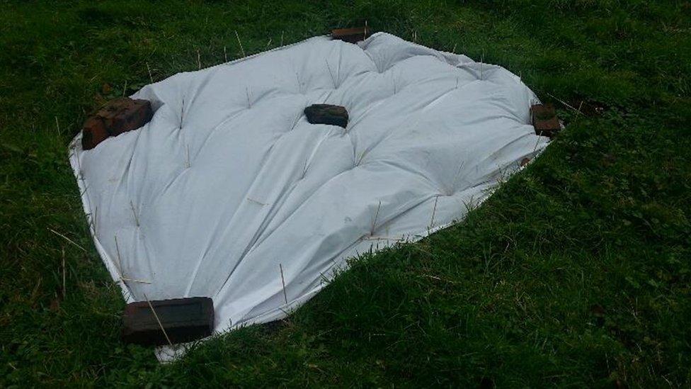 Duvet pinned out on grass with bricks