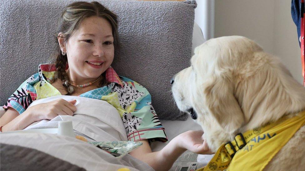 Daisy Murfin lies in bed with a dog next to her