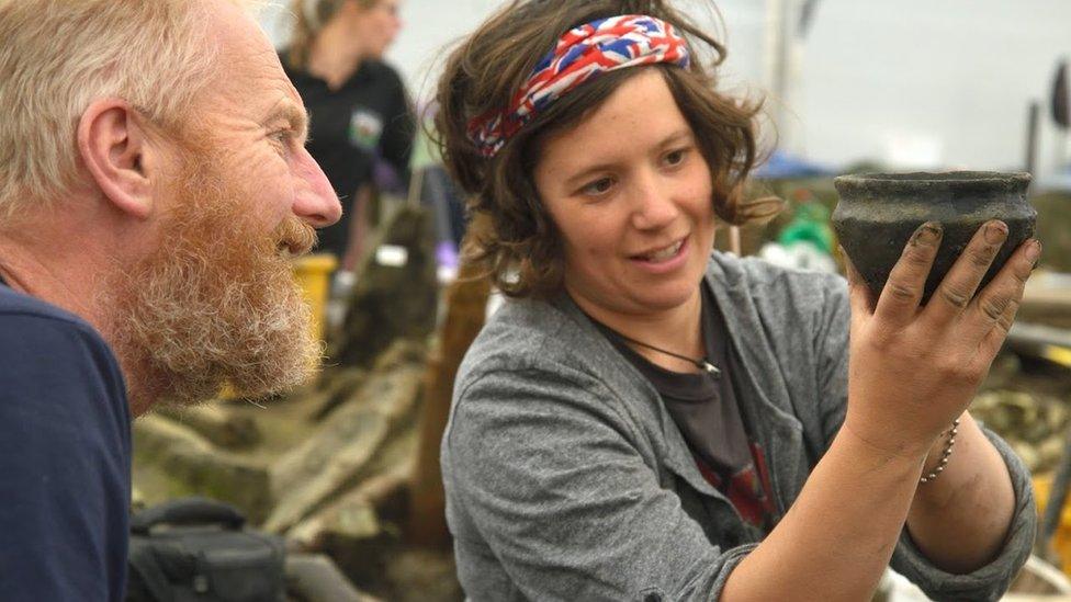 Two archaeologists inspect bowl