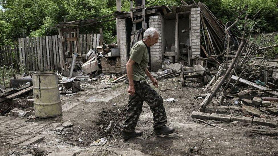 A man walks through the yard of a damaged house after shelling in which two people were killed in the city of Lysychansk in the eastern Ukrainian region of Donbas on June 13, 2022,