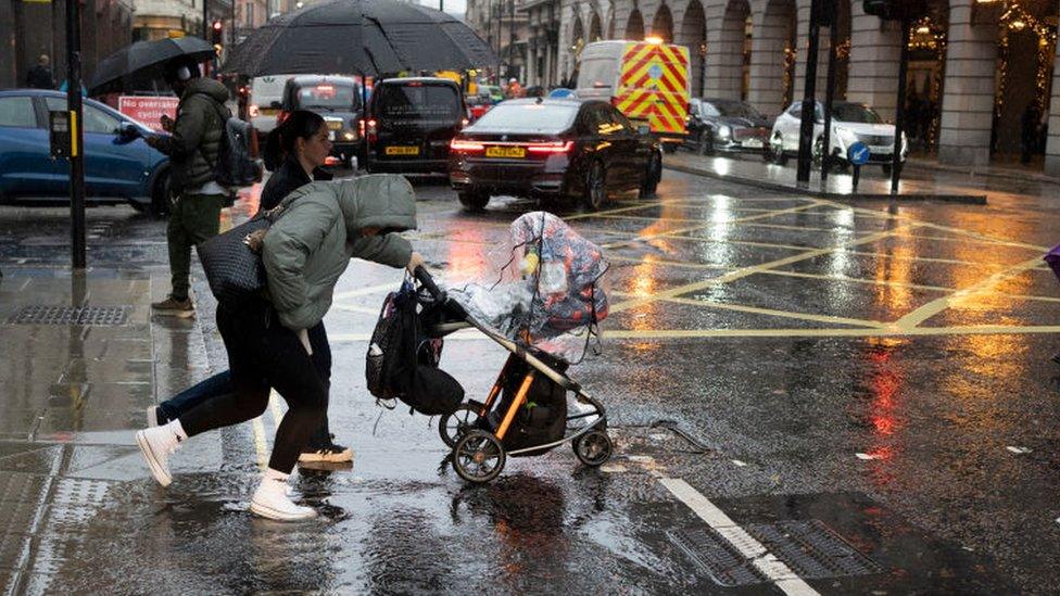 Lady with pram crossed road in the rain