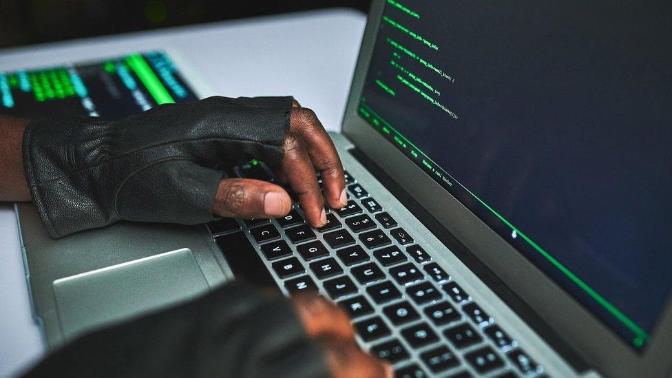 An unrecognizable IT technician in a server room and using a laptop