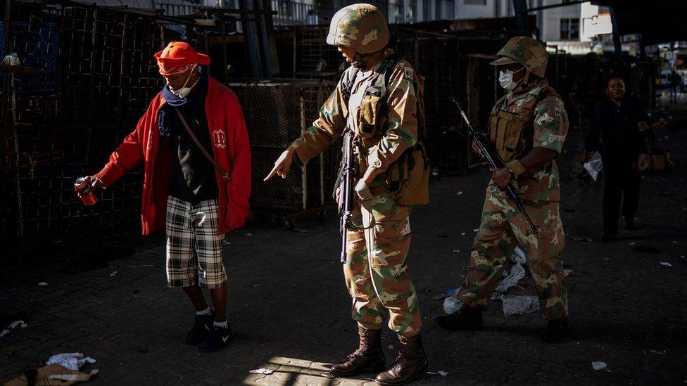 A South African National Defence Force (SANDF) soldier instructs a homeless man to discard his beer on the ground during an operation to enforce a national lockdown in the Johannesburg CBD, on March 27, 2020