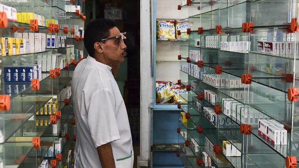 A worker of an empty pharmacy is pictured in Caracas on May 30, 2016