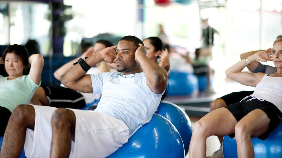 A group of adults doing abdominal crunches in a gym