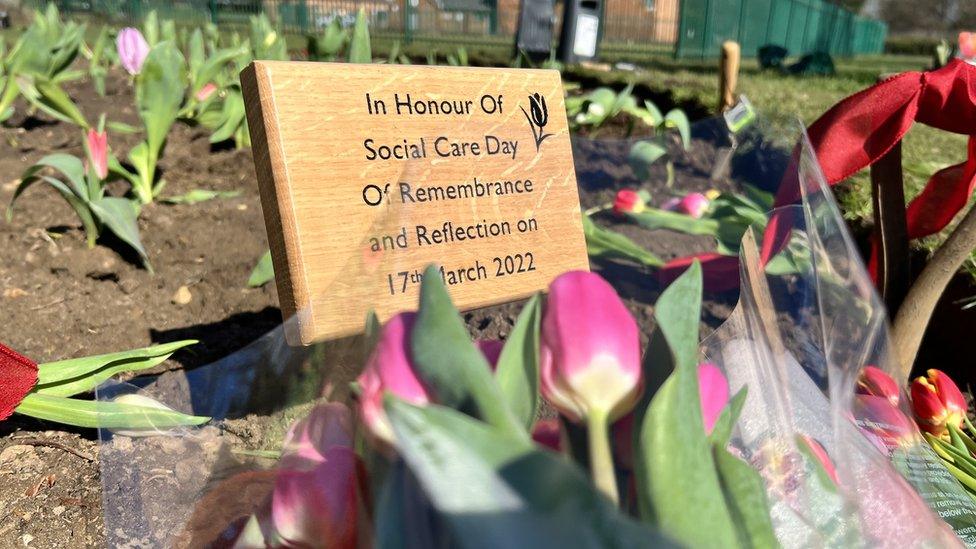 A plaque and flowers laid at a memorial