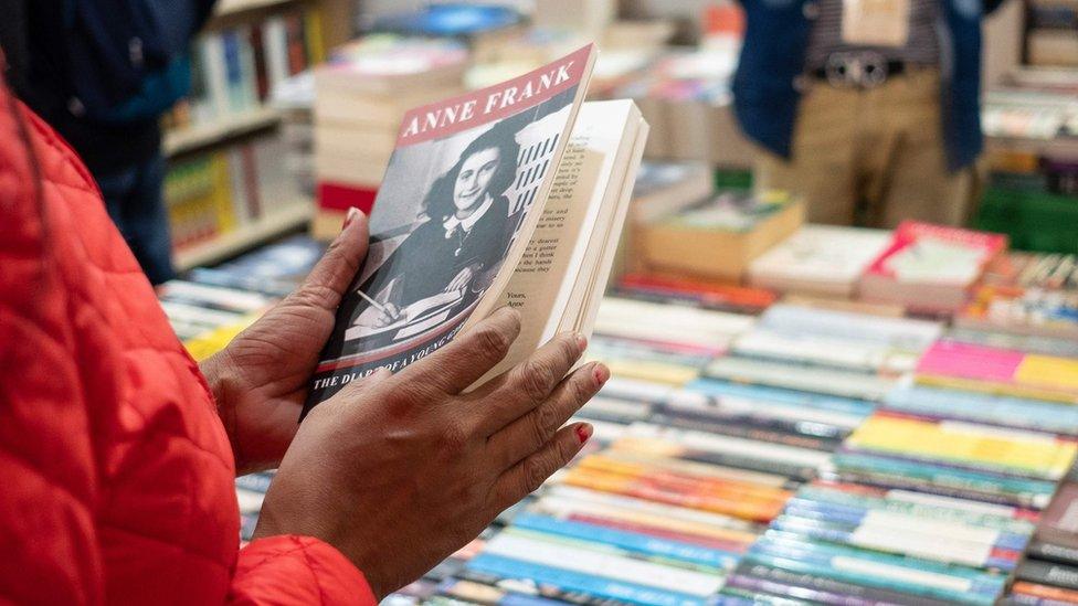 Someone-holding-Anne-Frank's-diary-in-a-book-shop.