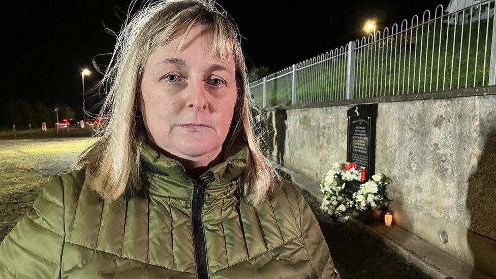 A woman stands in front of a memorial for the victims of the Greysteel attack