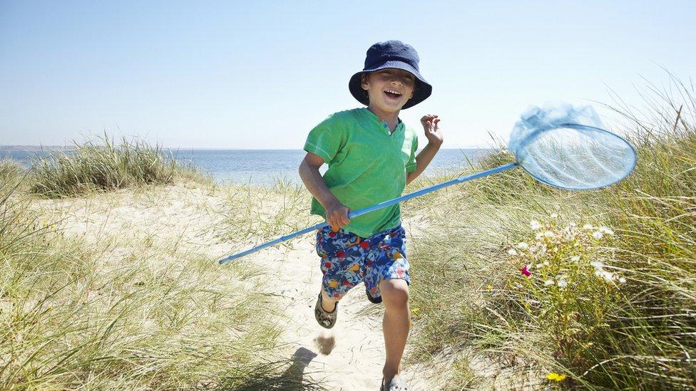 Boy running on beach with net.