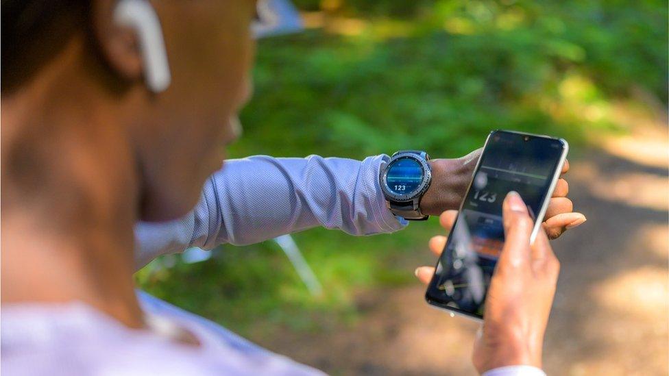 Woman using phone, smart watch and fitness tracking software