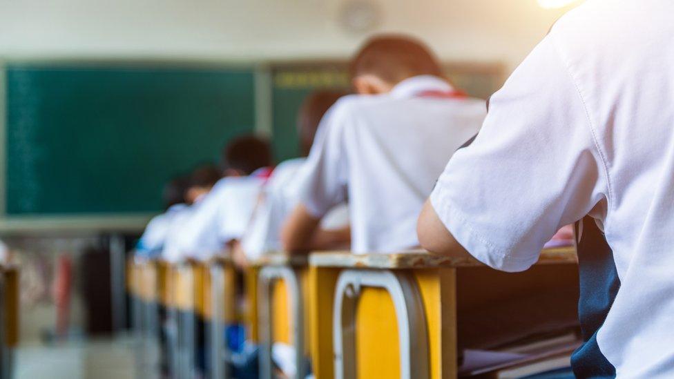 Rear view of middle school students studying in classroom