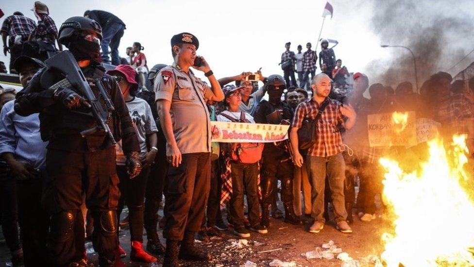 Indonesian police officers stand guard as supporters of Jakarta's Governor Basuki Tjahaja Purnama gather outside Cipinang prison in Jakarta (09 May 2017)