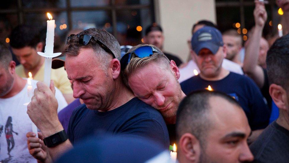 Paul Cox, right, leans on the shoulder of Brian Sullivan, as they observe a moment of silence during a vigil for a fatal shooting at an Orlando nightclub, Sunday, June 12, 2016, in Atlanta.