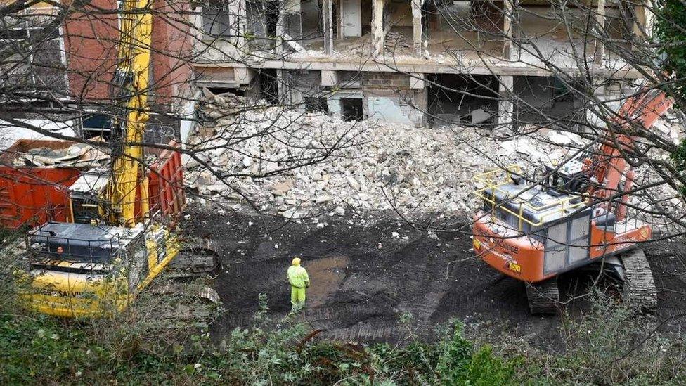 Cranes demolishing building