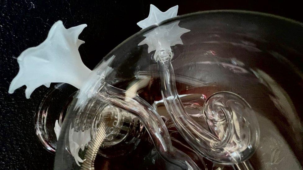 Detail of clear glass sculpture containing bubbles and twisted glass tubes finished with white star-shaped finials