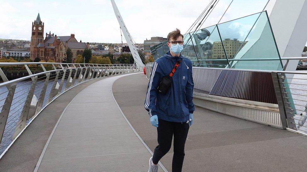 Mask-wearing man walking across Derry's Peace Bridge