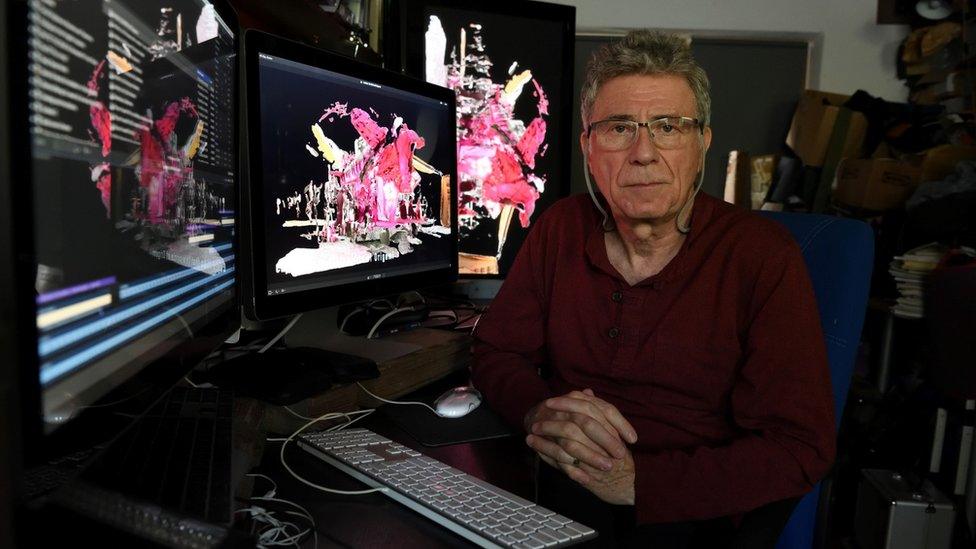 A man with glasses sitting in front a computer