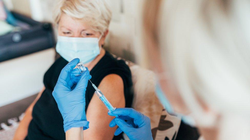 Patient receives vaccine injection from her home health care nurse - generic image