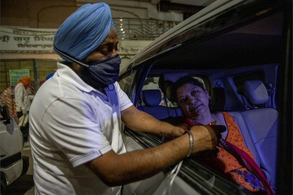 A volunteer uses an oximeter to check the oxygen level of a woman before providing oxygen support for free, amidst the spread of coronavirus disease (COVID-19), outside a Gurudwara (Sikh temple) in Ghaziabad, India, April 24, 2021