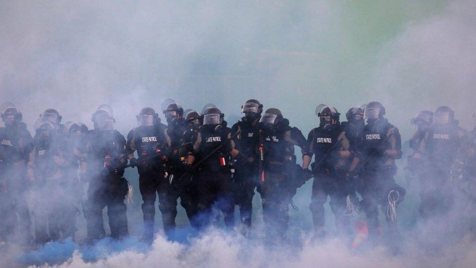 Police officers walk through tear gas in Minnesota