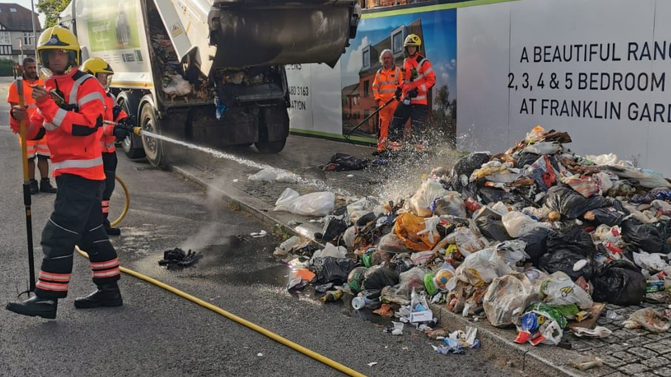 Firefighters dowsing down refuse fire